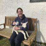 Our Ranger Hayley with a lamb on her lap and a cup of tea!